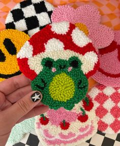 someone is holding up some crocheted items in front of the camera, which are shaped like mario and luigi's mushroom head