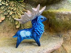 a blue deer figurine sitting on top of a rock