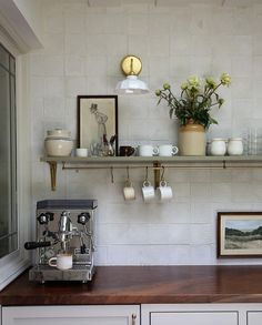 a coffee machine sitting on top of a counter next to a shelf filled with cups and saucers