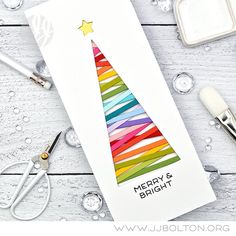 a card with a christmas tree made out of colored paper and scissors on the table