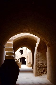 an alley way with stone walls and steps leading into the light at the end is a lantern