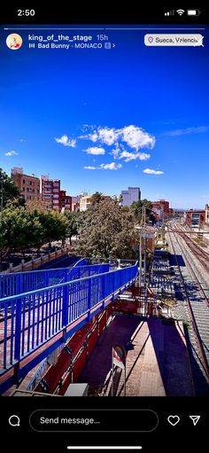 an image of a train station with blue railings and buildings in the back ground