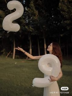 a woman in a white dress is holding some balloons that are shaped like the letter s