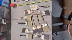 several different types of paint brushes on a table with tape measures and other tools