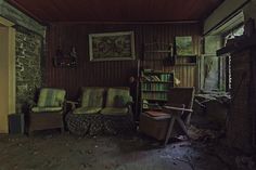 an old living room with two chairs and a book shelf full of books in it