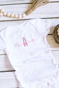 This beautifully custom embroidered 0-to-3 month short-sleeved baby bodysuit makes the perfect outfit for your new little baby girl! This comfortable and soft baby bodysuit with snaps features high quality embroidery thread that upgrades a baby one-piece! Personalized with your baby girl's name and monogram initial in beautiful script font, this summer baby clothing is a great way to celebrate your newborn's arrival. A meaningful custom baby gift new parents will love. This listing is for a custom 0-3 MONTH sized short-sleeve baby bodysuit. Buyer customization options are:  * choice of bodysuit color (oat, white) * choice of first initial and baby name  * choice of embroidery thread color (see swatch chart in listing photos) Please allow 1-3 business days processing time from date of order Fitted Short Sleeve Onesie For First Birthday, White Short Sleeve Onesie For Baptism, Fitted White Onesie For Baptism, White Fitted Onesie For Baptism, Fitted Cotton Bodysuit For Baptism, Cotton Baptism Onesie With Short Sleeves, Cotton Onesie For Baptism, White Short Sleeve Onesie For First Birthday, Pink Cotton Baptism Onesie