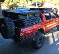 a red pick up truck with some big tires on it's flatbeds