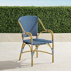 a blue and white chair sitting on top of a cement floor next to a hedge