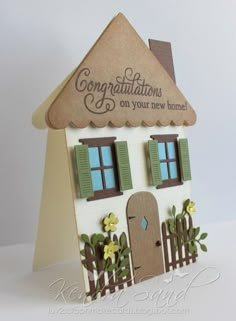 a card with a house made out of paper and some flowers on the outside, along with words that read congratulations on your new home