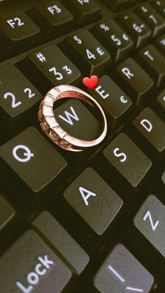 a ring sitting on top of a computer keyboard with the word love spelled below it