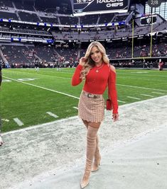 a woman in a red top and tan skirt at a football game wearing over the knee boots