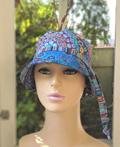 a mannequin head wearing a colorful hat in front of a window with trees