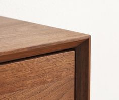 a close up of a wooden drawer with white wall in the backgroung