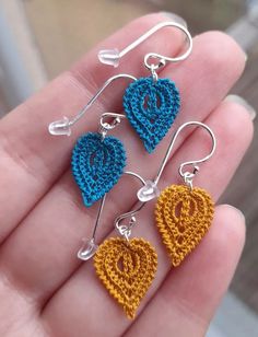 three crocheted heart earrings are shown in the palm