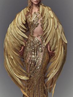 a woman in a gold dress with large wings on her head and shoulders, posing for the camera