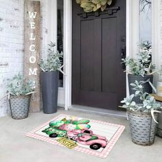 a front door with potted plants and a welcome mat