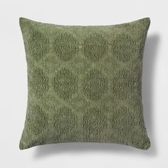 a green pillow with an animal print pattern on the front and back, sitting against a white wall