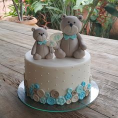 two teddy bears are sitting on top of a cake with blue and white frosting