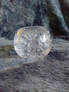 a clear glass bowl sitting on top of a gray tablecloth covered surface with black and white designs