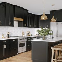 a large kitchen with black cabinets and white counter tops, wooden flooring and stools