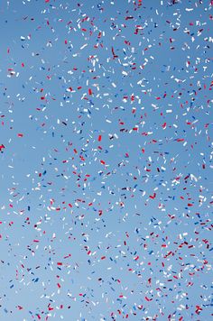 a blue sky filled with lots of red, white and blue confetti