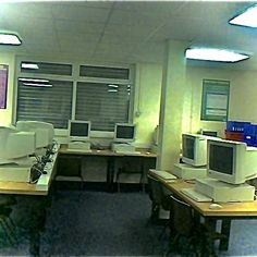 an office cubicle with multiple computers on the desks and two monitors in front of them