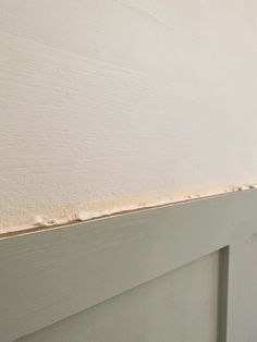 the corner of a white painted wall with some paint chipping on it's side