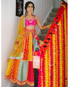 a woman in a colorful dress standing next to a staircase with garlands on it