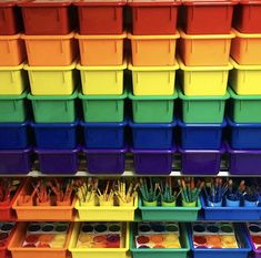 many different colored containers and pencils are arranged on the shelf in front of each other