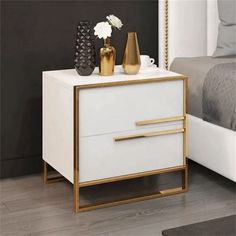 a white and gold nightstand with two vases sitting on it's side table