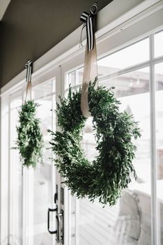 two wreaths hanging from the side of a window