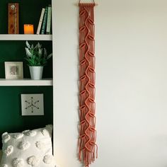 there is a wall hanging made out of red yarn on the wall next to a bed