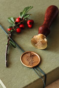 a wax stamp sitting on top of a green book next to a red berry bush