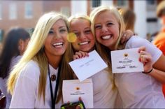 three beautiful young women standing next to each other holding up white cards and envelopes