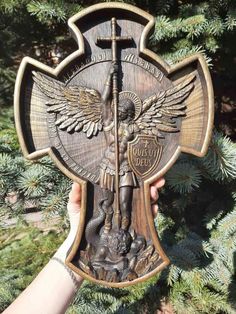 a person holding up a wooden cross with an angel on it