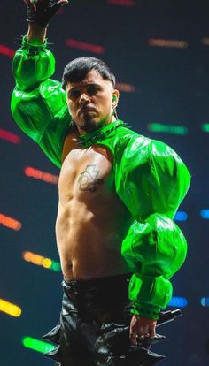 a man with no shirt on holding his hands up in the air while wearing green gloves