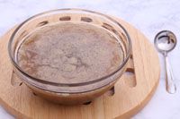 a wooden plate with a glass bowl and spoon on it