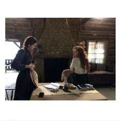 two women standing in front of a fire place