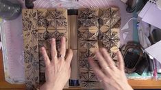 two hands are touching the top of a wooden box with intricate designs on it, while another hand is reaching for something