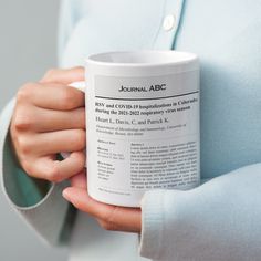 a person is holding a coffee mug in their left hand while wearing a blue shirt