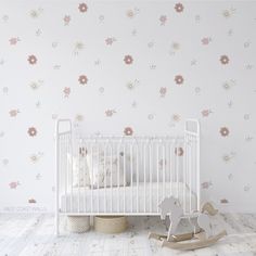 a baby's room with a white crib, rocking horse and flower wallpaper