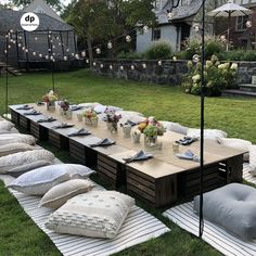 a long table is set up with pillows and place settings for an outdoor dinner party