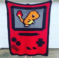 a person holding up a blanket made to look like an old video game console with pikachu on it