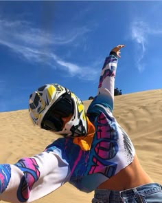 a person riding a motorcycle on top of a sandy hill with their arms in the air