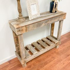 a wooden table with a vase on top of it and a picture frame next to it