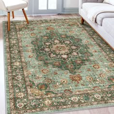 a green rug with an ornate design on the floor in front of a white couch