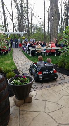 a police car is parked in the middle of a garden with people sitting at tables