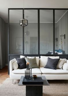 a living room with a white couch and black coffee table in front of large windows