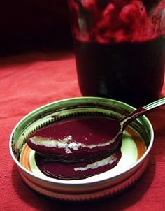 there is a bowl of food and a spoon on the table next to each other