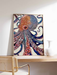 an octopus painting is on the wall above a desk with a white vase and chair